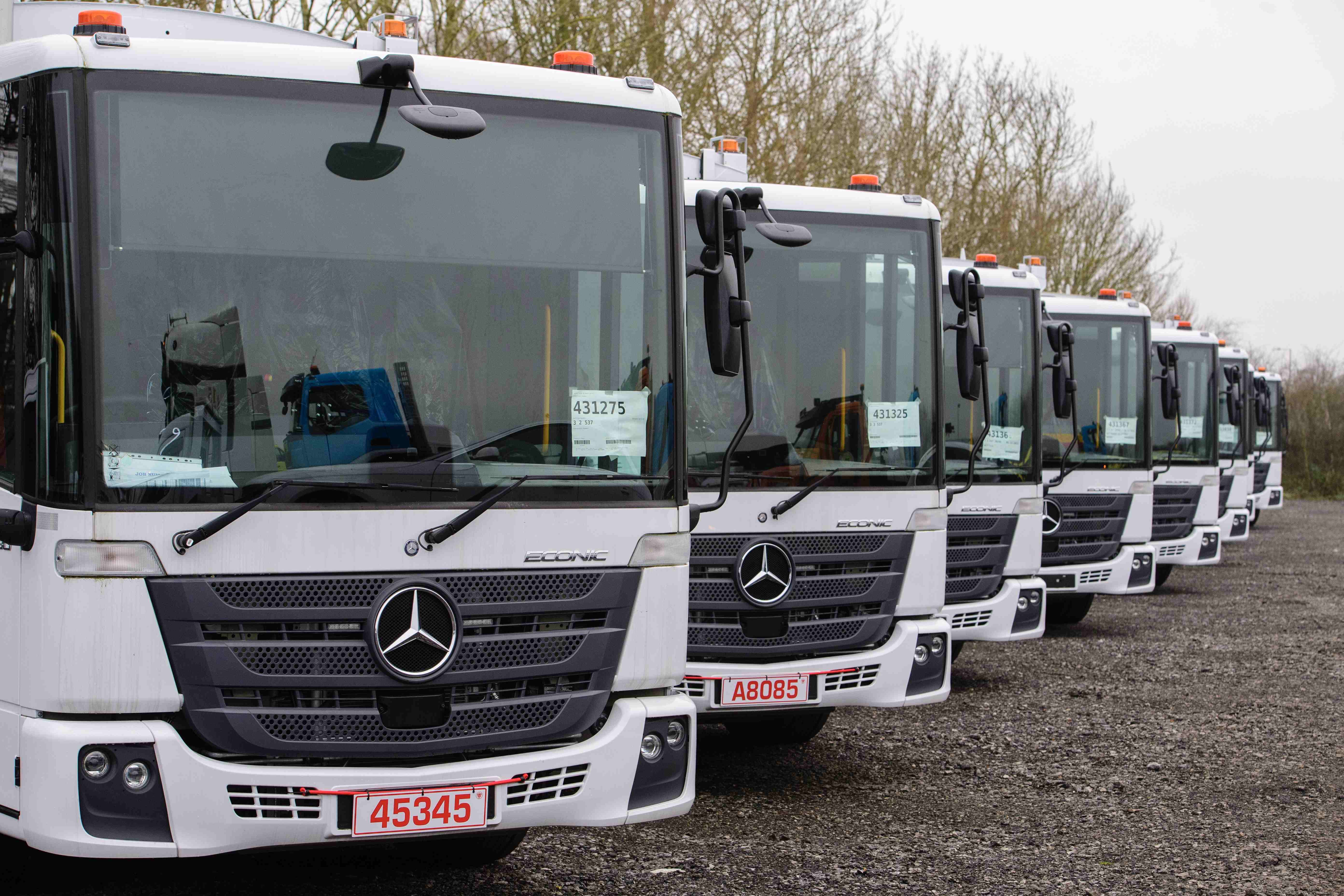 Row of Mercedes-Benz Econic trucks with trade plates
